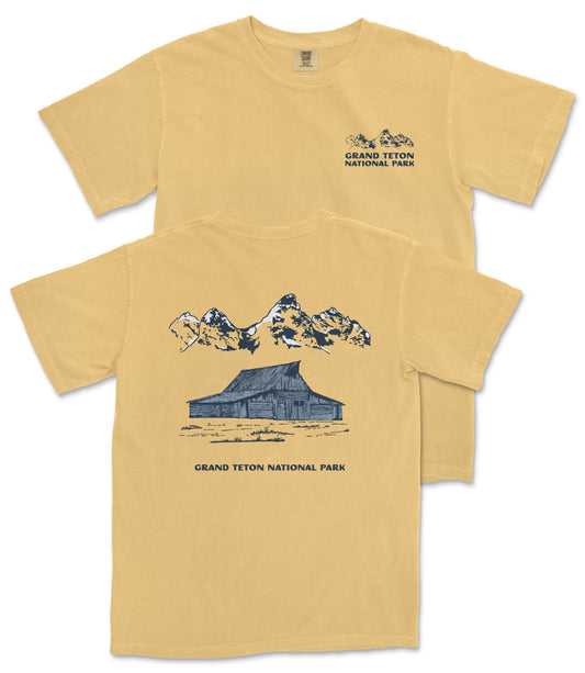 A yellow t-shirt with a graphic design depicting a cabin and mountains, along with the text "Grand Teton National Park".