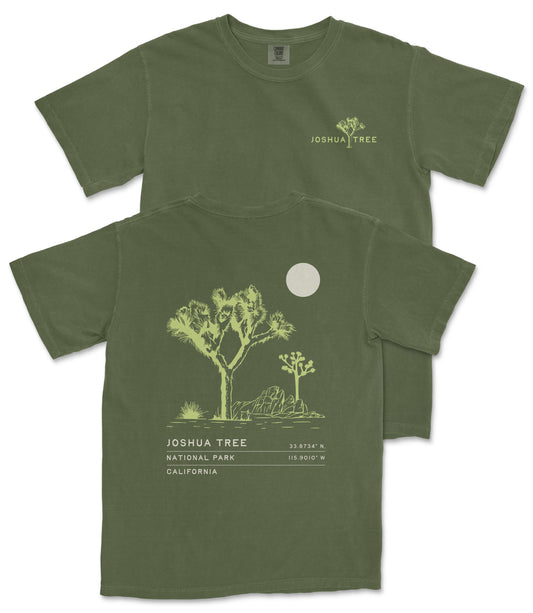 A green t-shirt with a graphic design depicting a desert landscape, including a tree and a moon, along with text that reads " Joshua Tree National Park California".