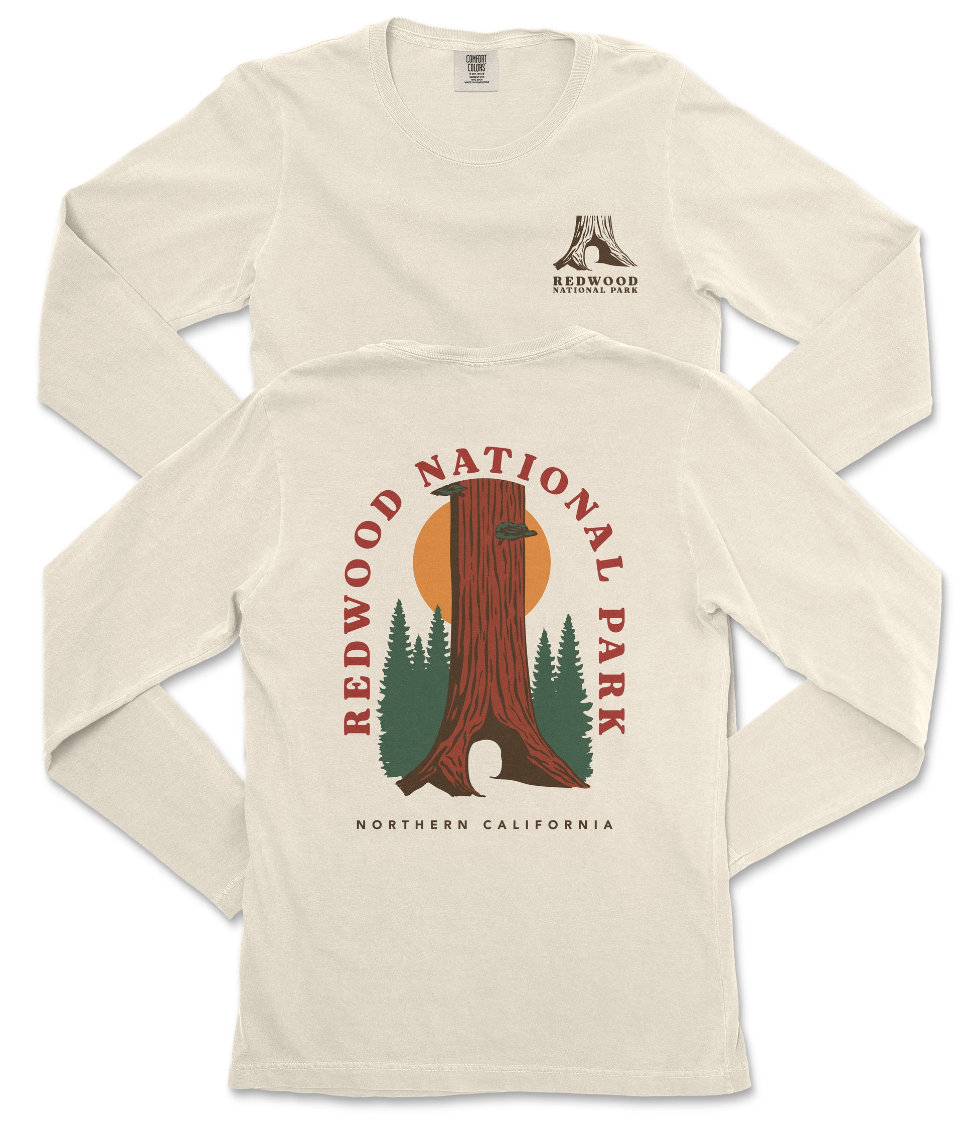 a white long-sleeved t-shirt with a graphic design depicting a tall tree with a sun-like symbol in the center, surrounded by pine trees. The design also includes the text "REDWOOD NATIONAL PARK NORTHERN CALIFORNIA".