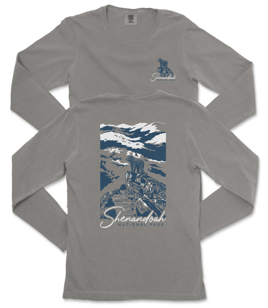 a gray long-sleeved t-shirt with a graphic design on the back. The design depicts a mountain landscape with a person standing on a rock. The text "Shenandoah National Park" is printed below the graphic.